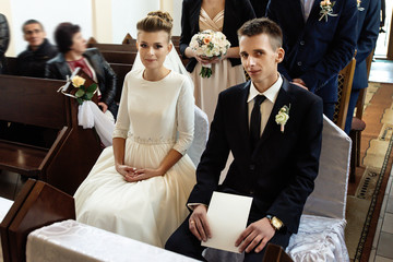 bride and groom preparing for communion on knees at wedding ceremony in church