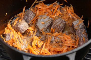 The cooking of pilaf:stewing of carrot and meat.