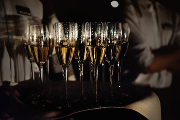 stylish glasses with champagne at evening light at wedding ceremony, catering and service at...