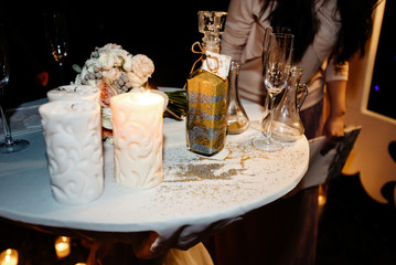 Fototapeta na wymiar bride and groom holding and pouring glass jars with sand for wedding tradition ritual at evening reception