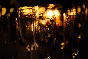 stylish champagne glasses empty on background of warm romantic candle light at evening wedding ceremony
