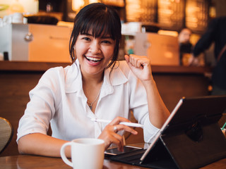 Asian woman drinking coffee in cafe and using laptop computer for working business online marketing