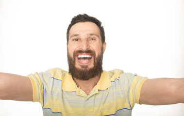 Close up portrait of a cheerful bearded man taking selfie over white background 