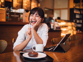 Asian woman drinking coffee in cafe and using laptop computer for working business online marketing