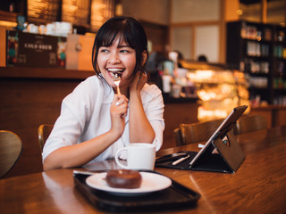 Asian woman drinking coffee in cafe and using laptop computer for working business online marketing