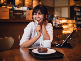 Asian woman drinking coffee in cafe and using laptop computer for working business online marketing