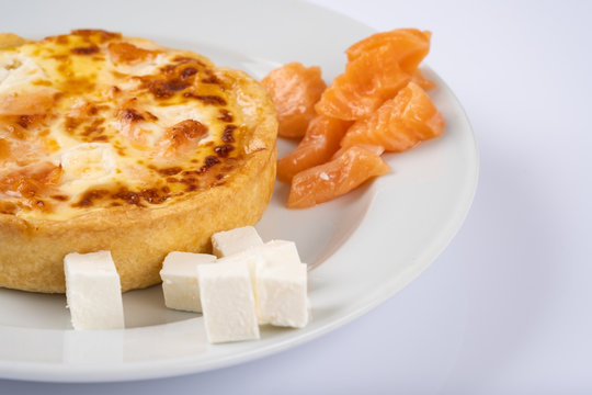 tart or casserole with salmon and feta on white plate