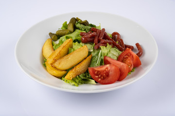 Grilled sausages, baked potatoes and vegetables on white plate