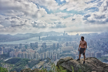 On top of the mountain after hiking in Hong Kong overlooking skyscrapers with sense of achievement