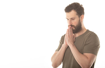 Picture of young bearded man dressed casually isolated on white background, having put hands together, dreaming and waiting for all best.