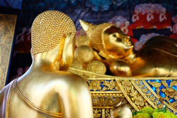 Close up Golden Disciple Statue with Ancient Reclining Buddha Image.