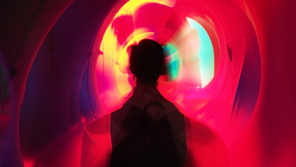 Zoom blur of an Asian boy rear view carrying a backpack going into a vivid colorful tunnel. Traveling through time image. Wide aspect ratio of 16:9.
