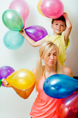 Fototapeta na wymiar pretty real family with color balloons on white background, blond woman with little boy at birthday party bright smiling mother