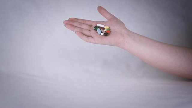 Aus der Handfl&auml;che fallende Tabletten in der Zeitlupe