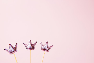 Three shiny crowns on a pink background. Decorations for holiday party. Copy space