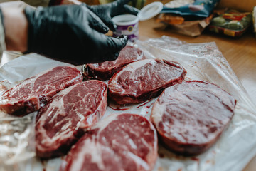 hands seasoning raw dry-aged Rib Eye Steaks