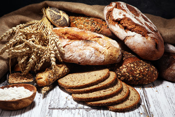 Assortment of baked bread and bread rolls on rustic white bakery table background