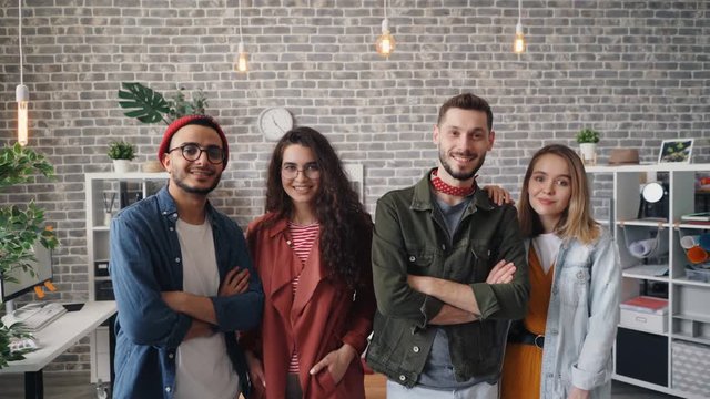 Portrait of young happy girls and guys company employees smiling looking at camera standing in office together. Successful business, people and millennials concept.