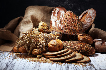 Assortment of baked bread and bread rolls on rustic white bakery table background