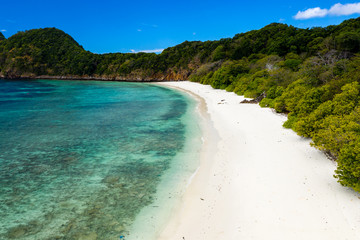 Aerial drone view of a lush, green tropical island with sandy beach