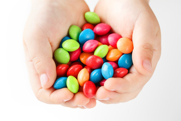 Fototapeta na wymiar Multicolored candies in the hands of a child on a white isolated background