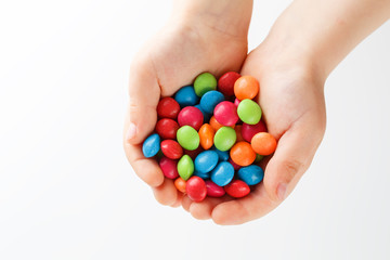 Multicolored candies in the hands of a child on a white isolated background