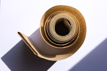 Yellow roll of blind fabric on white background with strong shadows