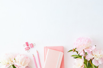 Blogger or freelancer workspace with notebook and light pink peonies on a white background