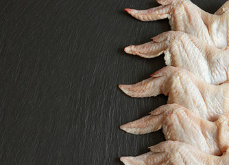 raw chicken wings on a black background