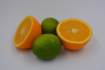 Bright two orange halves of sliced ​​ripe and juicy orange with two lime fruits. Healthy food and fruit, health and sport.