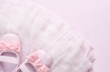 Dress of a little girl, pink tulle, shoes with ribbon on pink background.