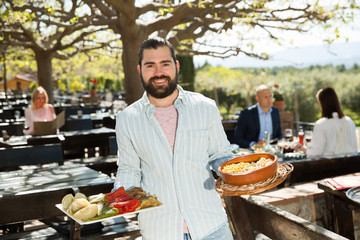 Owner of restaurant in open air meeting guests