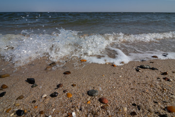 Welle und bunte Steine am Strand am Meer