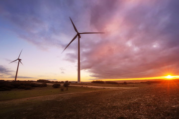 Obraz premium wind turbines silhouette on mountain at sunset .