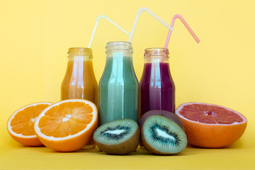 Different juices in bottles with ingredients on yellow table. Natural Organic Food Style.