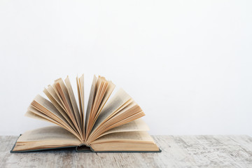 Open book on a wooden surface against the background of a white wall, the concept of education and training