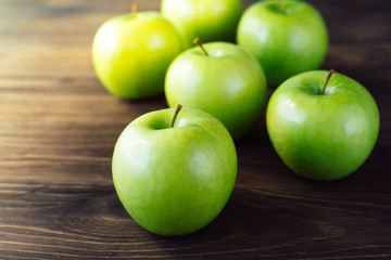 Group of green apples on brown wooden background. Close up