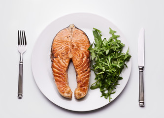 Salmon steak with arugula on plate