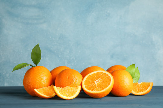 Ripe oranges with leaves on wooden table against light background, space for text © Atlas