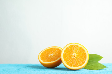 Halves orange with leaves on blue table against white background, space for text
