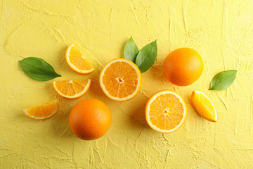 Flat lay composition with ripe oranges and leaves on color background. Top view, space for text