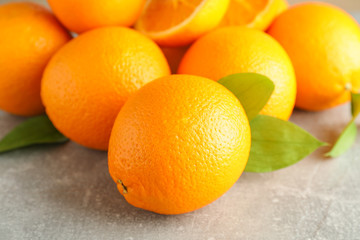 Ripe oranges with leaves on grey table, closeup