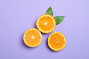 Flat lay composition with oranges and leaves on color background. Space for text