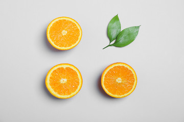 Flat lay composition with oranges and leaves on light grey background. Space for text