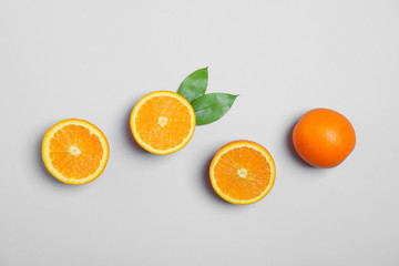 Flat lay composition with oranges and leaves on light grey background. Space for text