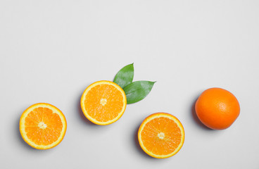 Flat lay composition with oranges and leaves on light grey background. Space for text