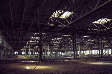 Abandoned large industrial hall or warehouse with garbage, ruined factory
