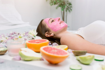 Obraz na płótnie Canvas Face mask, spa beauty treatment. Woman applying pink facial clay mask at spa salon, skincare, side views