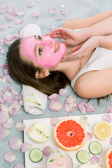 Obraz na płótnie Canvas cosmetic procedures, mask for skin care, woman young, spa salon. Close-up portrait of beautiful girl lying on the bed in spa salon applying pink mud facial mask