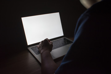 Picture of white light from a laptop on a wooden table in a dark room. © PBXStudio